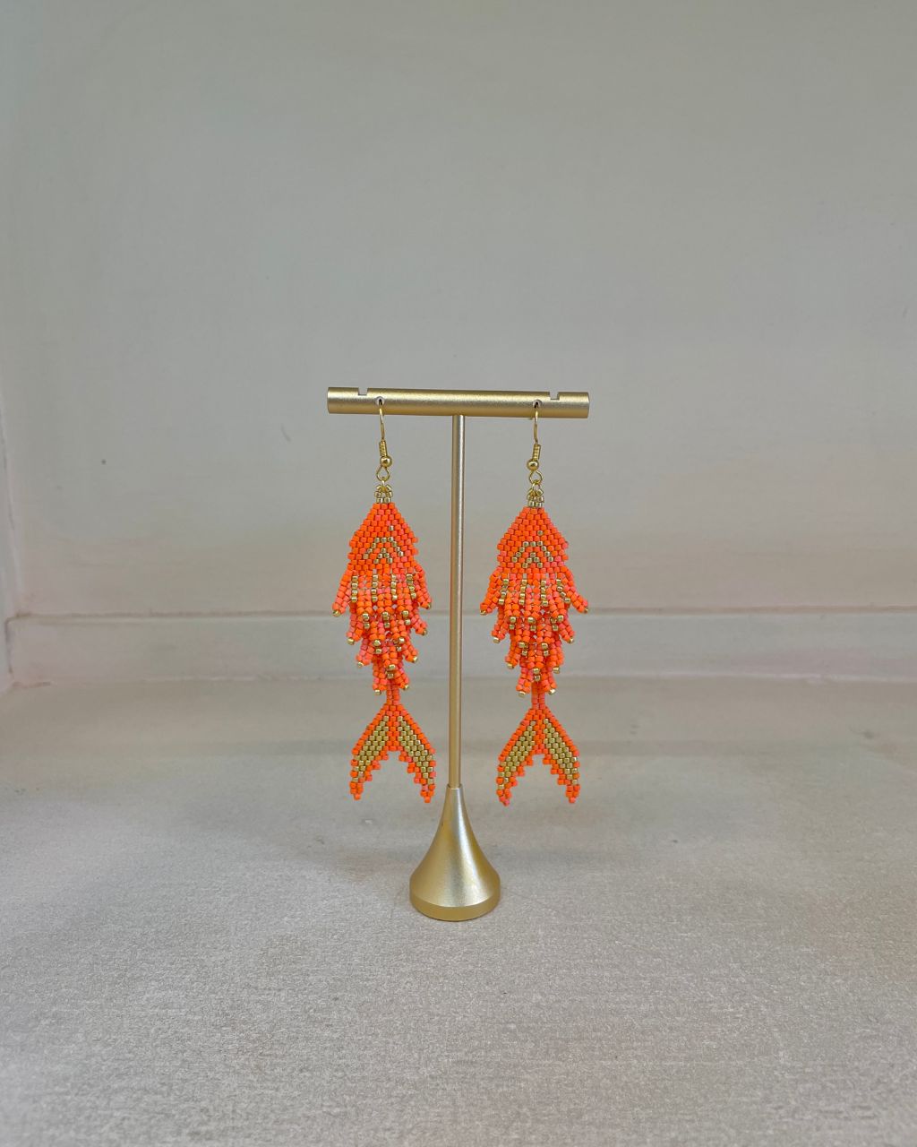Aretes artesanales en miyuki en forma de pez, colgantes, color naranja.