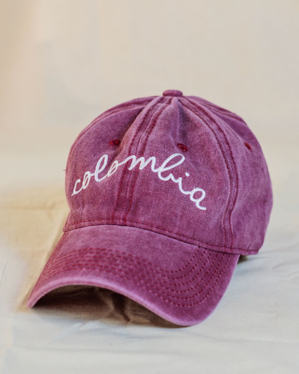 Gorra roja con letras blancas en cursiva que contiene la palabra Colombia.
