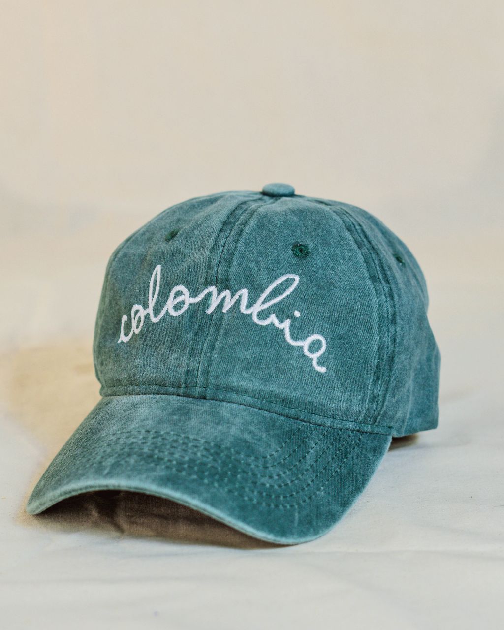 Gorra verde con letras blancas en cursiva que contiene la palabra Colombia.