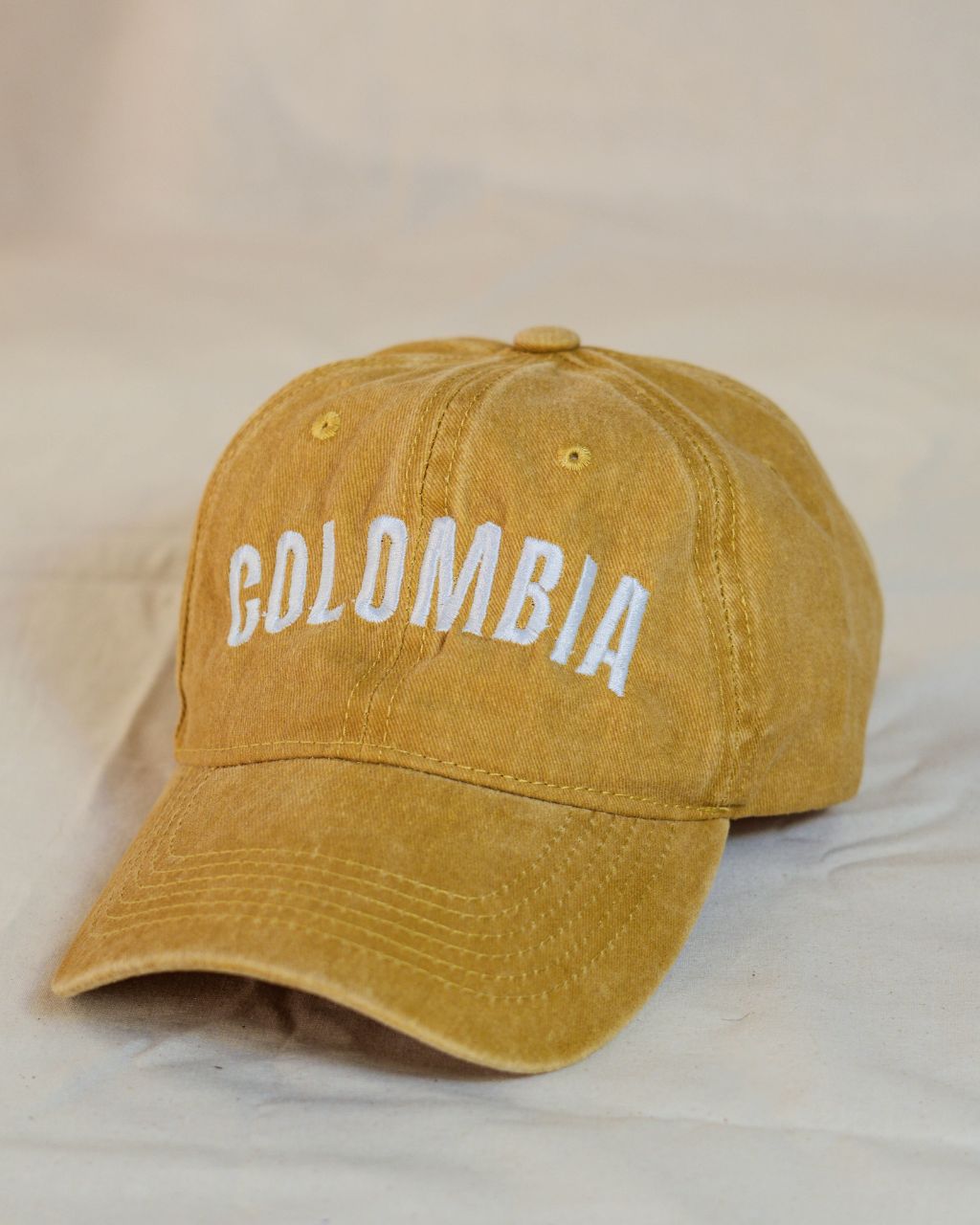 Gorra amarilla con letras blancas en mayúscula que contiene la palabra Colombia.