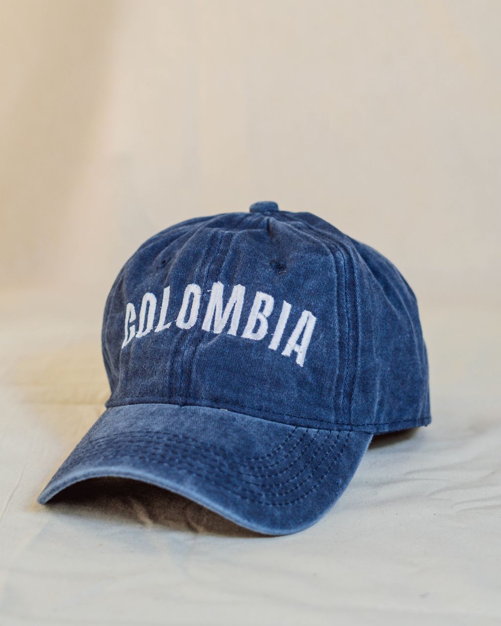 Gorra azul con letras blancas en mayúscula que contiene la palabra Colombia.