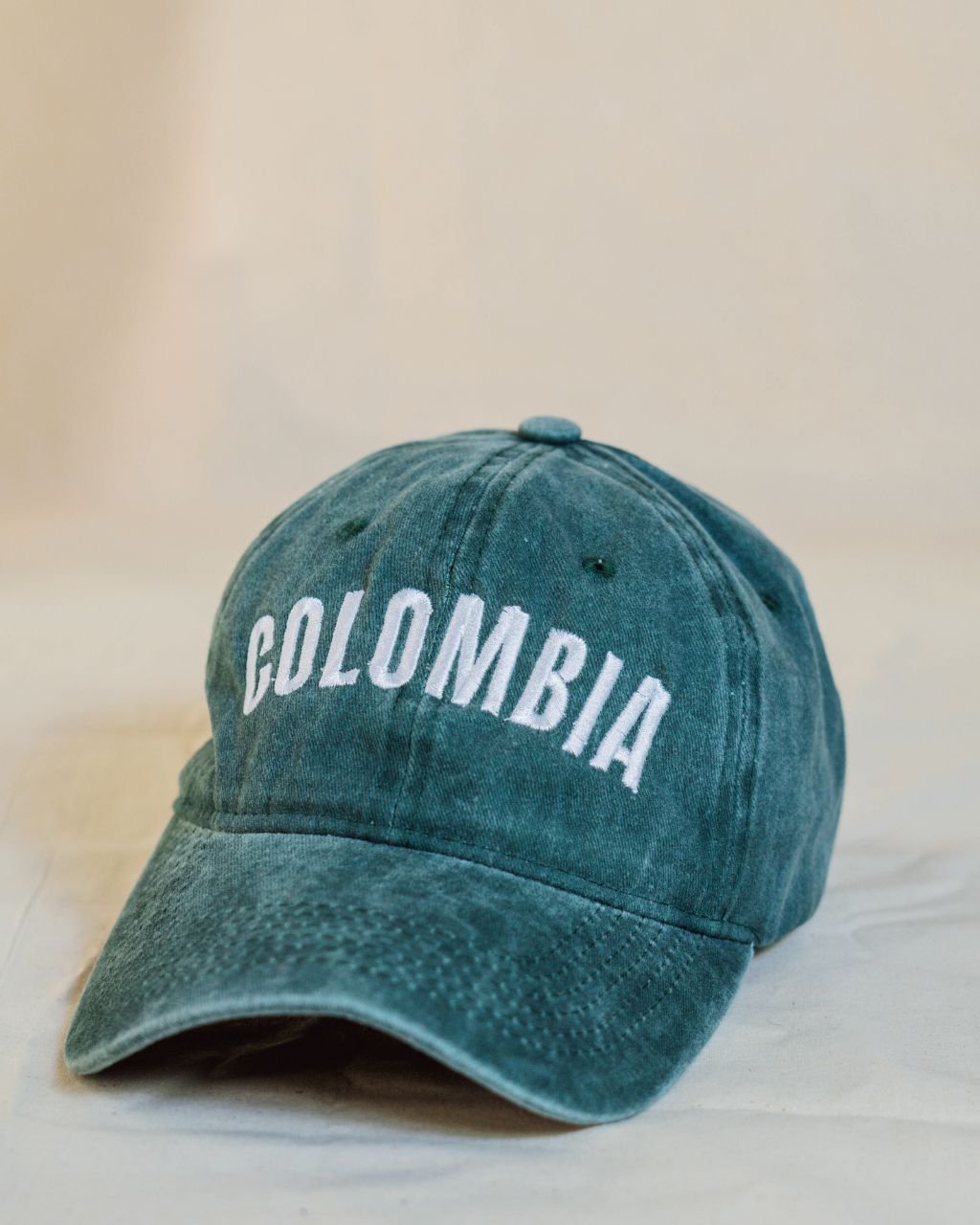 Gorra verde con letras blancas en mayúscula que contiene la palabra Colombia.