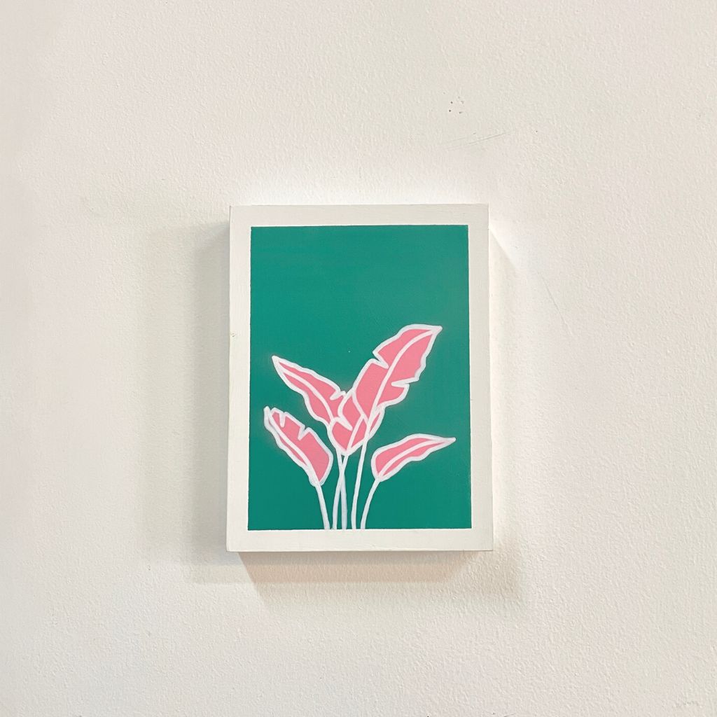 Arte con la técnica de línea clara que ilustra mini hoja de plátano rosada sobre color turquesa, tamaño 17.5 x 22.5 cm.