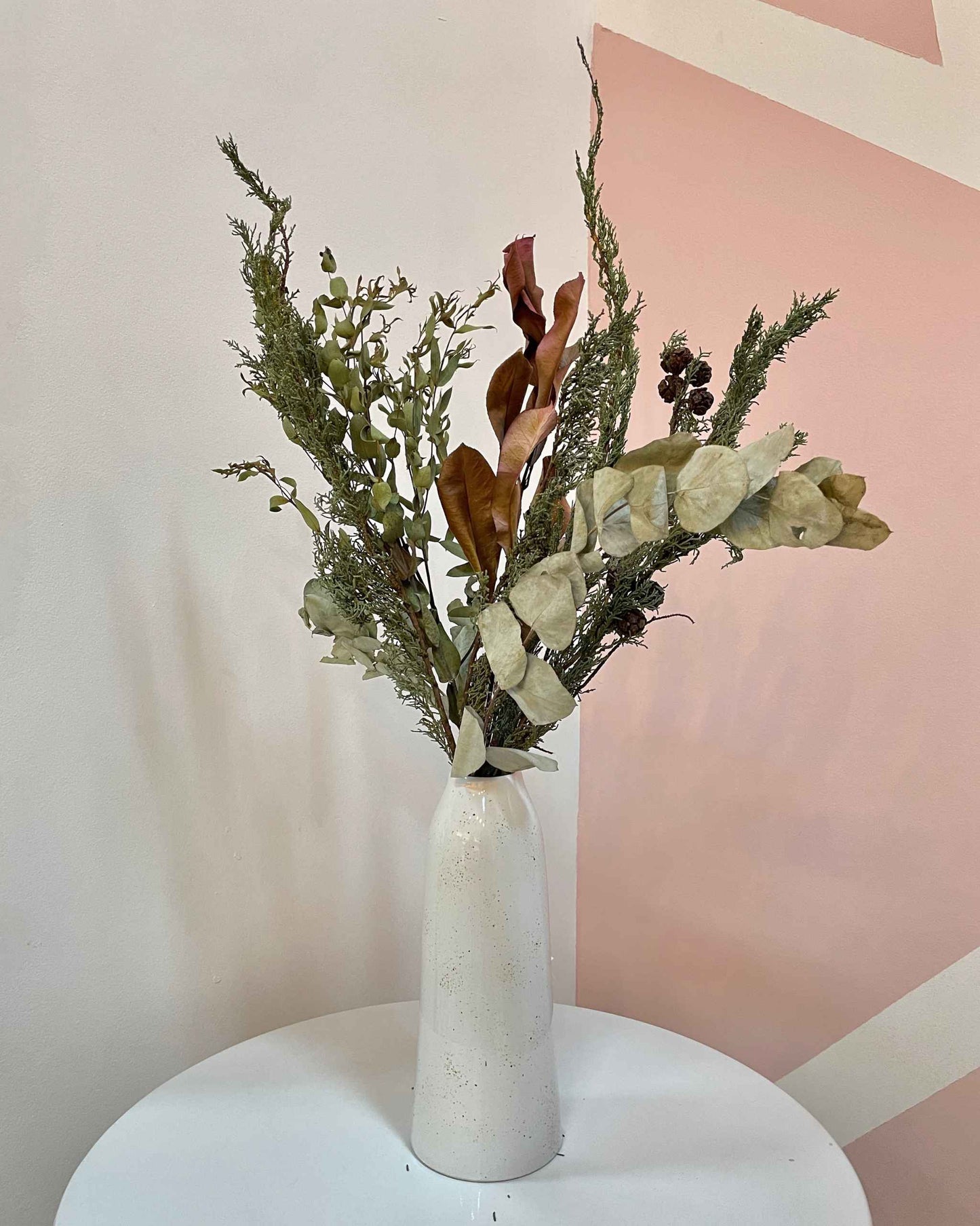 Florero alargado blanco con pecas doradas hecho artesanalmente a mano con cerámica y decorado con flores secas de larga duración.