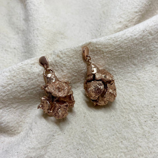 Aretes que reflejan la vida y la fertilidad, en unas hermosas campanitas impresas de la misma naturaleza. Hecha artesanalmente por colombianos en baño de oro rosa.
