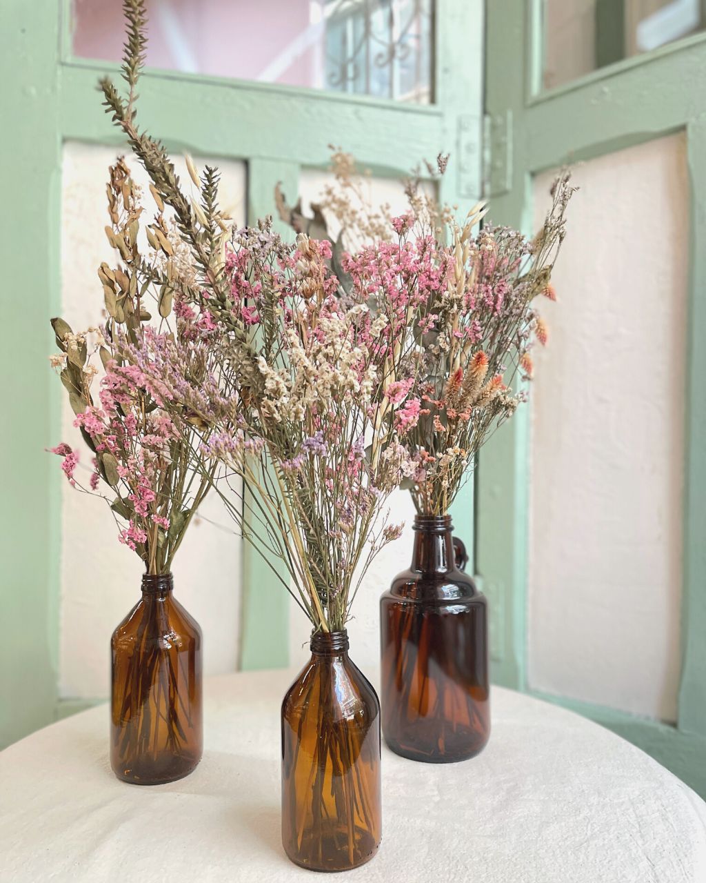 Arreglo de flores secas en botella en varios tamaños para decorar espacios.