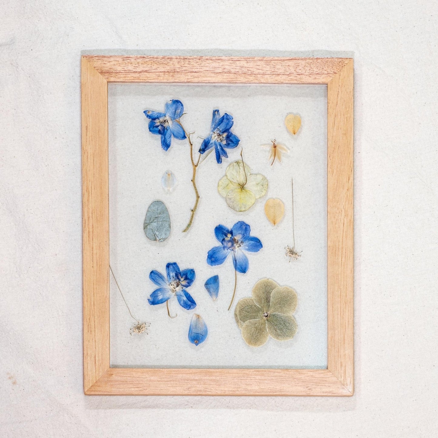 Cuadro de flores azuladas entre vidrios de 18 x 23 cm