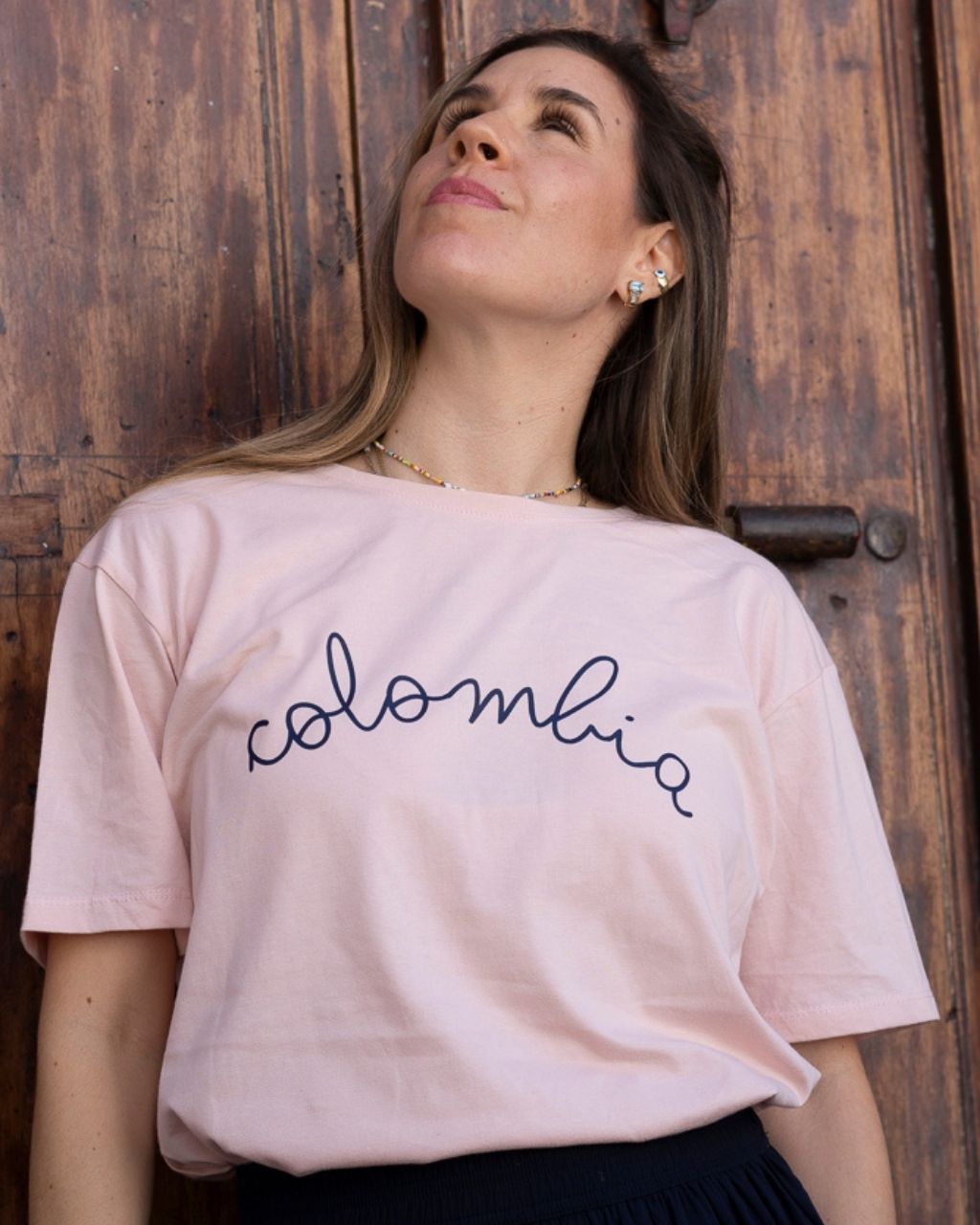T-shirt Colombia Cursiva con fondo rosado.