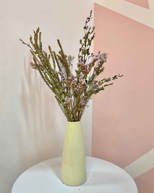 Florero alargado color lima hecho artesanalmente a mano con cerámica y decorado con flores secas de larga duración.